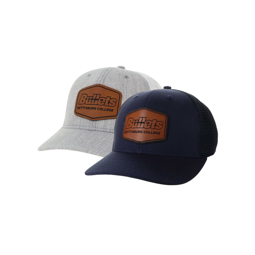 Two Gettysburg College Bullets trucker hats shown on a white background, one in heather light gray and one in navy blue. Both feature a brown leather patch on the front with the Bullets Gettysburg College branding.